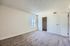 Bright bedroom with soft carpet flooring and a large window for natural light.