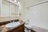 Sleek and bright bathroom with elegant fixtures, featuring a marble countertop sink, mirrored cabinet, and pristine white bathtub.