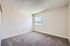 Spacious bedroom with light-colored walls, soft carpeting, and a large window offering mountain views.