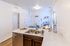 Bright and inviting open-plan kitchen and living space featuring elegant countertops, modern sink, and cozy seating area with decorative touches.