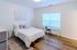 Bright and airy bedroom featuring elegant decor, a cozy bed, modern furnishings, and ample natural light from a wide window.