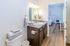 Bright and inviting bathroom featuring sleek countertops, modern fixtures, and a glimpse into the airy bedroom beyond.