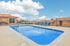 Inviting outdoor pool area with bright blue loungers, set against clear skies, offering a perfect relaxation spot at the apartment complex.