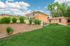 Charming apartment complex with vibrant landscaping, featuring a lush green lawn and modern brick architecture under a bright blue sky.