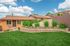 Charming single-story home with vibrant landscaping and a well-maintained lawn under a bright blue sky.