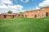 Charming apartment complex boasting brick exteriors, lush green lawns, and a vibrant community environment under a beautiful blue sky.