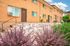 Charming multi-unit apartment building with warm brick exterior and lush landscaped front garden.