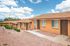 Charming brick apartment complex with a serene landscape and bright blue skies, offering a welcoming and cozy living environment.