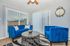 Chic living room featuring vibrant blue sofas, a modern round coffee table, and elegant vertical blinds. A stylish wall clock adds charm.
