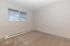 Bright and airy room with plush carpeting and a large window, perfect for a cozy bedroom or home office.