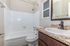 Bright and modern bathroom featuring a sleek granite countertop, elegant dark wood vanity, pristine bathtub, and polished chrome fixtures.