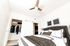 Elegant bedroom featuring a plush bed, modern ceiling fan, and spacious closet with stylish attire, complemented by contemporary artwork.