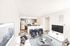 Modern open-concept living room and kitchen with elegant gray cabinets, stylish seating, and a chic geometric rug.