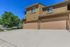 Charming townhouse exterior with a double garage, nestled in greenery and showcasing a modern design under a clear blue sky.