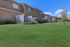Charming townhomes with private backyards, surrounded by lush greenery and a vibrant blue sky.