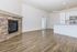 Bright, open-concept living area with sleek wood flooring, featuring a modern kitchen and elegant stone fireplace.