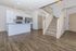 Modern open-concept apartment showcasing a sleek kitchen with stainless steel appliances and an elegant staircase leading to the upper level.