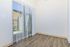 Bright apartment interior with elegant wood flooring and a large sliding glass door opening to a serene outdoor view.
