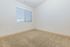 Bright and inviting empty room with plush beige carpeting and large window offering natural light, perfect for personalization.