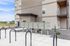 Contemporary apartment building exterior with secure mailboxes and bicycle parking, set in a serene landscaped area.