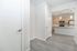 Modern apartment entrance with sleek hardwood floors leading to a stylish kitchen featuring contemporary wooden cabinets and stainless steel appliances.