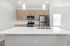 Bright modern kitchen with sleek stainless steel appliances, elegant white countertops, and stylish pendant lighting.