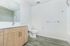 Modern bathroom featuring sleek wooden vanity, large mirror, and contemporary fixtures with white walls and flooring.