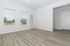 Bright and spacious room with elegant hardwood flooring, large windows, and a door leading to a serene outdoor view.