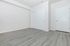 Modern minimalist room with sleek gray flooring, white walls, and double sliding closet doors, perfect for a fresh start.
