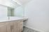 Elegant bathroom with modern wood cabinetry, sleek countertop, and a large mirror offering a spacious and fresh ambiance.
