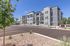 Modern apartment complex showcasing sleek architecture, ample parking, and vibrant landscaping under a clear blue sky.