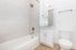 Elegant bathroom with modern fixtures, sleek vanity, and pristine white tile, creating a bright and inviting space.