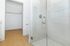 Pristine modern bathroom with sleek glass shower and spacious walk-in closet, featuring elegant wood flooring.