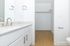 Modern bathroom with sleek faucet and spacious walk-in closet, featuring elegant white cabinetry and warm wood flooring.