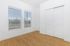 Bright, minimalist room with large windows, sleek wooden floors, and a modern white sliding closet door.