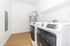 Modern laundry room with sleek washer and dryer, featuring bright white walls and stylish wooden flooring.