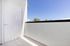 Bright and inviting balcony with a pristine white door and expansive sky view, perfect for relaxation in a modern apartment setting.