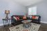 Inviting living room with stylish brown leather sofas, vibrant orange and patterned cushions, a chic wooden coffee table, and warm lighting on polished wooden floors.