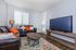 Inviting living room with cozy leather sofa, vibrant pillows, and smart TV, offering a perfect blend of comfort and style.