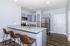 Modern kitchen with sleek granite countertops, stainless steel appliances, and stylish bar seating, offering an inviting and functional space.
