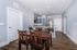 Chic open-concept dining area with elegant wooden table, modern kitchen, and sleek stainless steel appliances.