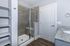 Modern bathroom featuring a sleek glass shower, granite countertop, and elegant shelving, perfect for stylish living.