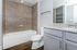 Modern bathroom featuring elegant granite countertops, sleek fixtures, and a luxurious tiled bathtub.