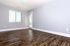 Bright and airy room with elegant wood flooring and large window, perfect for a cozy living space or home office.