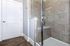 Modern bathroom showcasing a sleek glass shower with stylish beige tiles and elegant wood flooring.