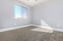 Bright and airy bedroom with large window, plush carpet, and modern gray walls.