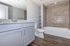 Modern bathroom with elegant granite countertops, sleek gray cabinetry, and a luxurious bathtub set against stylish tile walls.