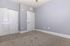 Spacious and bright room with soft gray walls, plush carpeting, and white closet doors.