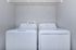 Contemporary laundry room with sleek white washer and dryer, complemented by an open wire shelf for added storage.