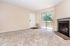 Inviting living room with plush carpet, sliding glass doors to a balcony, and a cozy fireplace.
